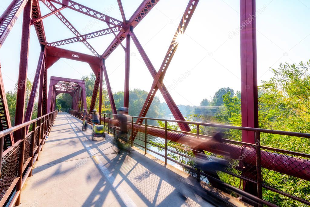 Bike Riders blur past as they cross a fancy bridge