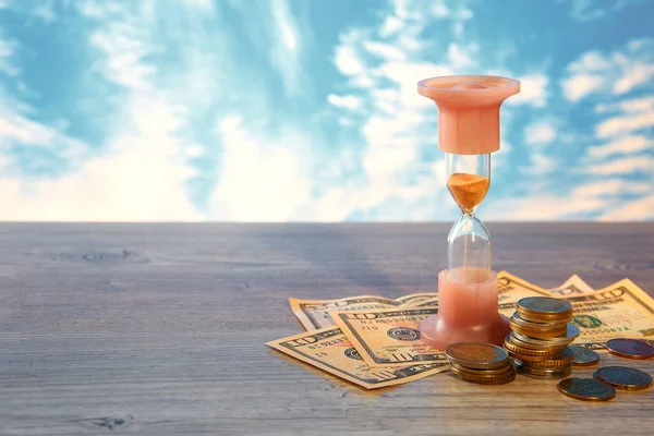 Time is money. Financial concept of money with a clock and coins of different countries. Hourglass.