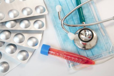 Masaya bir stetoskop, yüz kalkanı, test tüpü ve haplar yerleştirildi. Tıbbi konsept.