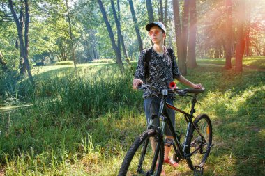 Bisikletli bir turist oturuyor. Bisikletli bir şehir parkında güneşin batışına karşı durdu ve....