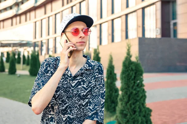 Şapkalı ve orijinal gözlüklü bir turist akıllı telefondan konuşuyor..