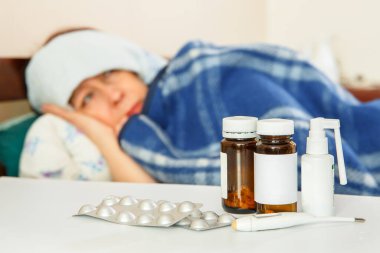 İlaçların yanında bir kadın hasta yatıyor. Yüksek vücut sıcaklığı.