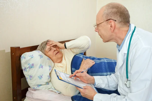 The family doctor communicates with a sick elderly woman. Home doctor discusses the condition of a sick woman