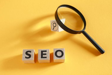SEO arama motoru optimizasyonu. Sarı arka planda SEO kısaltması olan tahta küpler..