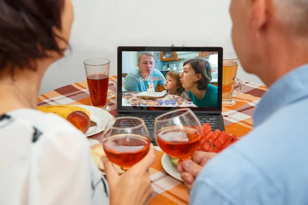 Parents celebrate the girl\'s birthday through a video call of a virtual party with grandparents. The girl and her parents blow out the candle on the cake. Coronavirus outbreak 2020