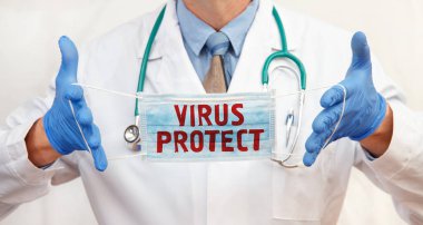 Doktor üzerinde Virüs Koruyucusu yazan koruyucu bir maske takıyor. Sağlık hizmetleri kavramı