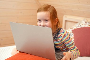 Küçük bir kız bilgisayara farklı duygularla bakıyor. Kız bilgisayarda oynuyor