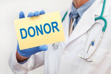 Eldivenli bir erkek doktorun elinde DONOR yazılı bir tabela var.
