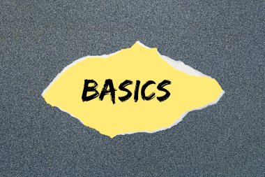 Yırtık sarı kağıda yazılmış BASICS. Gri arkaplan