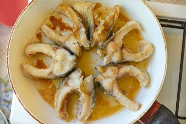 Balık parçaları beyaz bir tavada kızartılır. Kızarmış sazan parçaları. Evde yemek pişirmek..