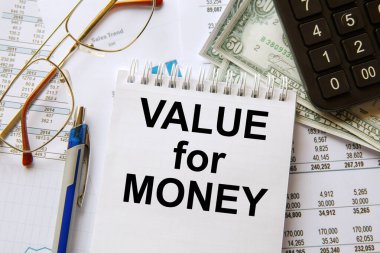 Para için VALUE bir not defterine, ofis aksesuarlarıyla birlikte bir ofis masasına yazılır. İş konsepti.