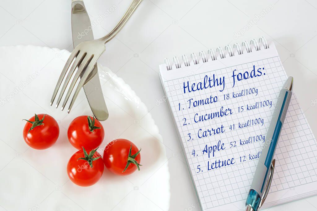 Chery tomatoes on a plate with cutlery. Notebook for recording and counting calories diet food