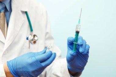 Maskeli doktor elinde şırınga ve stetoskop tutuyor..
