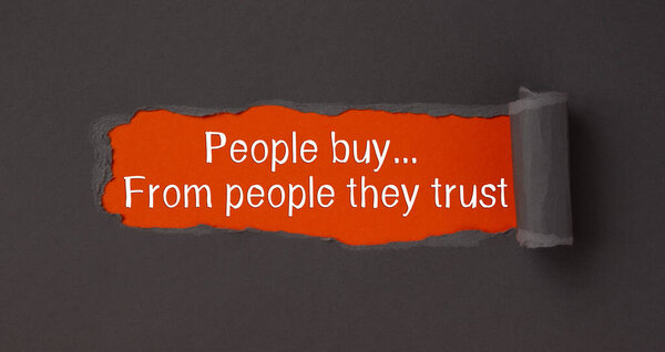 Text People buy from people they trust, appearing from tattered brown paper