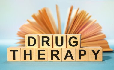 Açık bir kitabın arka planında tahta küplere yazılmış bir ilaç sözcüğü. Tıbbi konsept