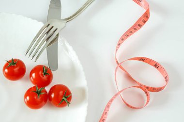 Çatal bıçaklı ve mezuralı bir tabakta kiraz domatesleri. Diyet gıda konsepti.