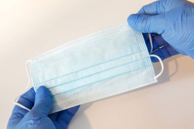 Beyaz arka planda koruyucu bir maske tutan bir doktor.