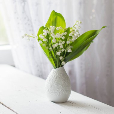 bir pencerede bir vazoda vadideki zambak