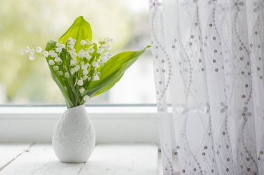 bir pencerede bir vazoda vadideki zambak