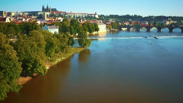 Воздушный полет низко над рекой Влтава с Пражским градом на заднем плане в Праге, Чехия — стоковое видео
