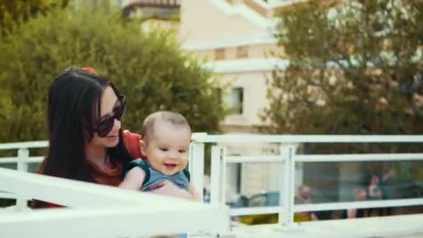 Moeder en baby lacht als toeristen speelt in Monte-Carlo met historisch gebouw op achtergrond — Stockvideo