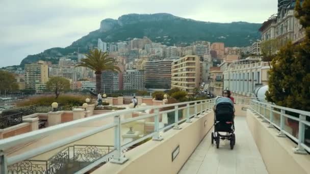 Frau geht mit ihrem Baby im Kinderwagen spazieren, während Touristen auf monte-carlo reisen — Stockvideo