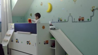 Yatak odasında oturma ve kamera kaydırıcıyı kamyon oyuncakları ile oynarken şirin çocuk
