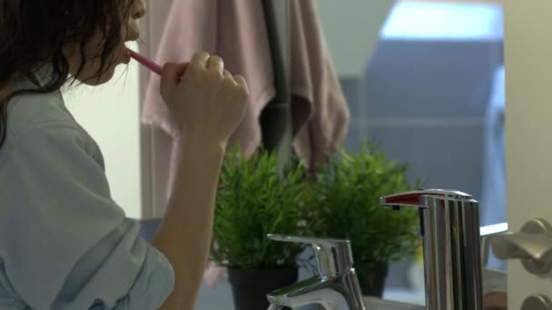 Ung kvinna borsta tänderna på morgonen i badrummet, kamera på reglaget — Stockvideo