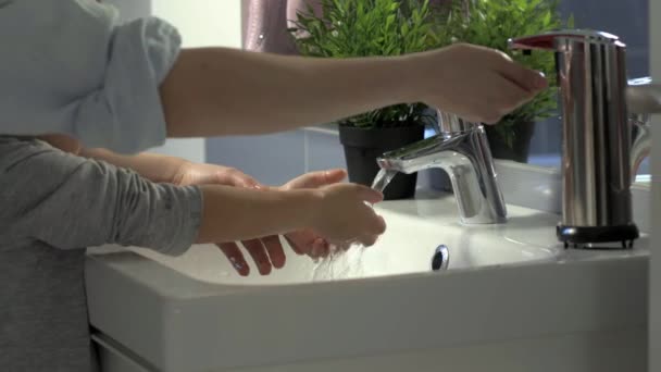 Young woman and her child are hygiene cleaning and washing their hands with liquid soap in the morning in bathroom, camera on slider — Stock Video