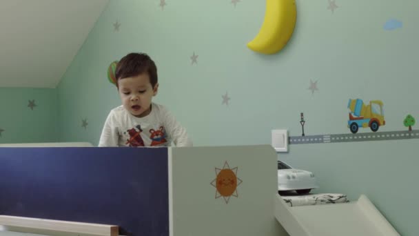 Malý chlapec kýchnutí a hrající hračka na posteli v jeho dětský pokoj, dítě zdravotní péče koncepce, fotoaparát na posuvník — Stock video