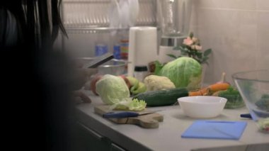 Genç ve güzel kadın bir cep telefonu tutarken salata mutfakta hazırlanıyor. Kaymak ateş