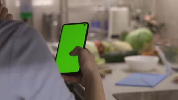 Girl looking mobile app recipes for fresh salad on smartphone with chroma key green screen before cook dinner, camera on slider — Stok Video