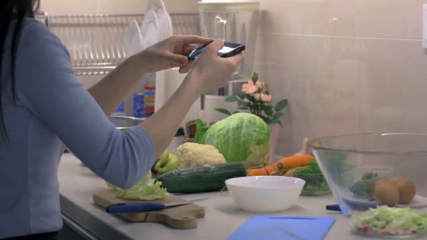Mujer tomar fotos de la preparación de ensaladas saludables en el teléfono inteligente en la cocina, aplicación de cocina. Cámara en slider — Vídeo de stock