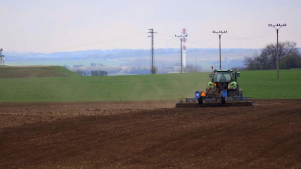 Nelahozeves, República Checa - 27.03.2019: Tractor verde trabajando en el campo de trigo. Agricultura y medio ambiente en la Unión Europea. El tractor está cultivando — Vídeo de stock