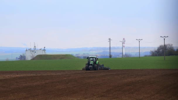 Nelahozeves, República Checa - 27.03.2019: Tractor verde trabajando en el campo de trigo. Agricultura y medio ambiente en la Unión Europea. El tractor está cultivando Metraje De Stock