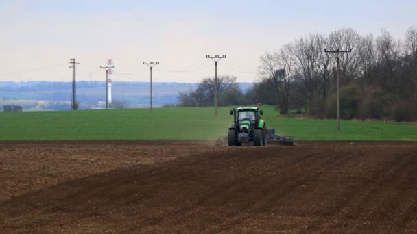 Nelahozeves, Česká republika - 27.03.2019:Green traktor v pšeničné pole. Zemědělství a životní prostředí v Evropské unii. Traktor je pěstování — Stock video