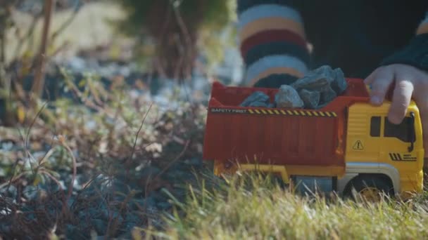 Reglaget skott av 3-årig pojke leker med lastbil utanför. Barn leker med leksaker i utomhus trädgård — Stockvideo