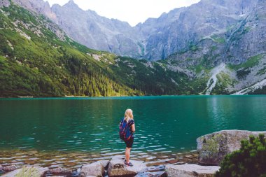 Sırt çantası ile Kız gezgin geri duruyor ve göl Morskie Oko bakar