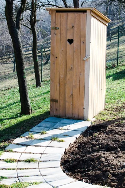 Nuevo aseo de madera en el jardín - agujero en forma de corazón en la puerta . Imágenes de stock libres de derechos