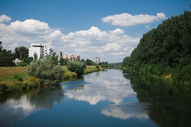 Küçük sakin şehir nehir sırasında yaz saati - suya yansıtan bulutlar.