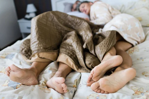 Mann und Frau schlafen teilweise bedeckt im Bett. — Stockfoto