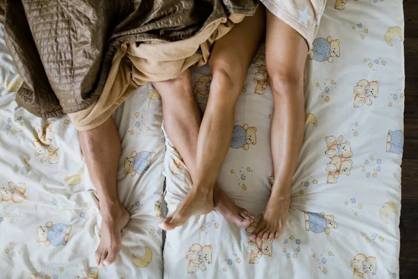 Husband and wife sleeping in bed together partially covered.