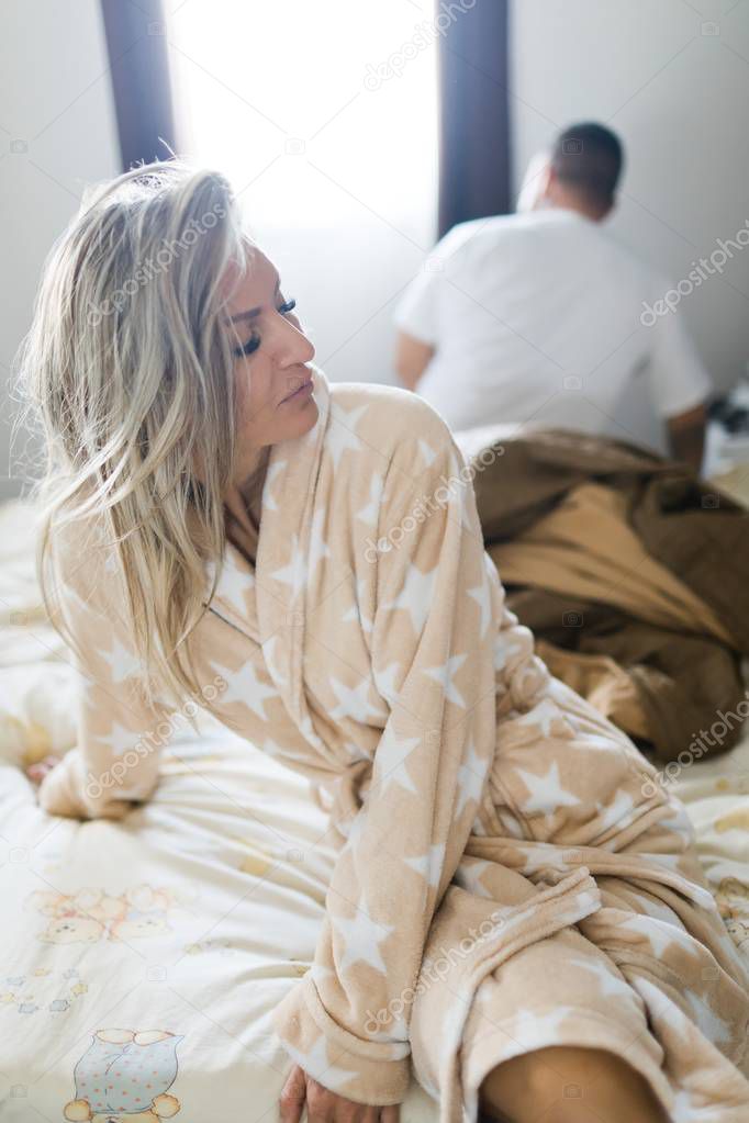 Couple having crisis in bed. Woman sitting on bed's edge.