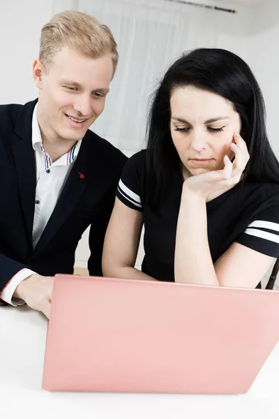 Superiors vs. subordinate - Blond man working with black haired bored woman.