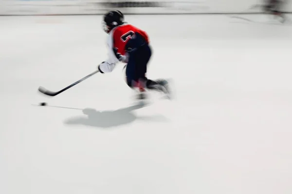 Junge Hockeyspielerin im roten Dress mit Puck in Bewegung. — Stockfoto