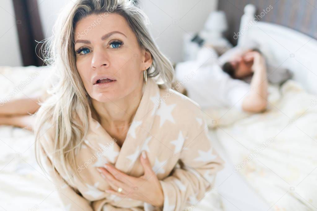 Couple having crisis in bed. Woman sitting on bed's edge.