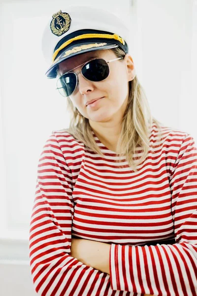 Sceptically young woman sailor in captain cap - wearing red gaps dress.