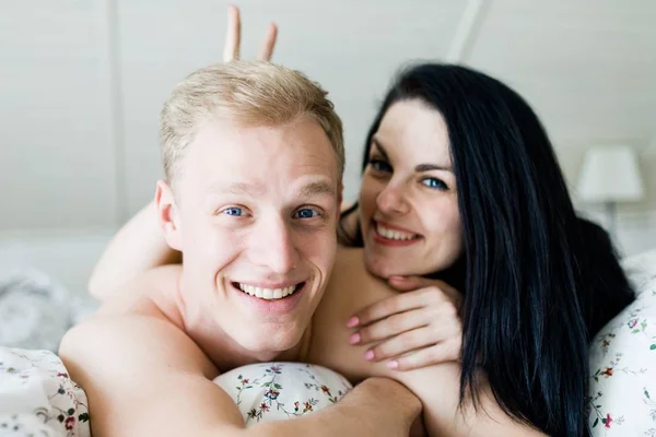 Handsome man and nice woman posing in bed - bunny ears — Stock Photo, Image