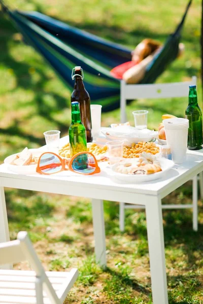 Table with bottles of beer and food on summer garden party.