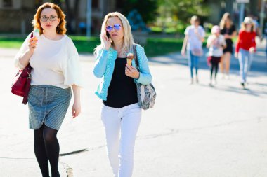 Güneş gözlüğü içinde Çekici sarışın kadın şehir merkezinde yürüyüş ve eatin